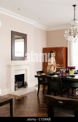Lady laying table in dining room Stock Photo