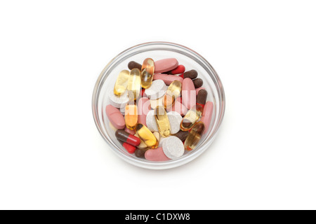 Multicolored tablets and capsules in transparent glass plate insulated on white background Stock Photo
