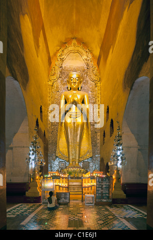 pilgrim before standing Buddha statue, Ananda Temple, Bagan, Myanmar Stock Photo