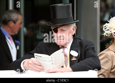 Man in top hat and eye-patch reading a racing form, Ascot, United Kingdom Stock Photo