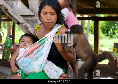 Siona people village, deep in the ecuadorian amazonian jungle (cuyabeno wildlife reserve).  Locals interact with pet monkey Stock Photo