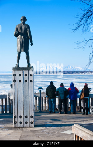 A STATUE OF JAMES COOK STANDS OVER TOURISTS LOOKING OVER COOK INLET IN RESOLUTION PARK Stock Photo