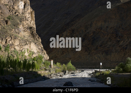 Tourist reading a book next to a suspension bridge in a deep gorge on the Srinagar-Leh Highway, (Ladakh) Jammu & Kashmir, India Stock Photo