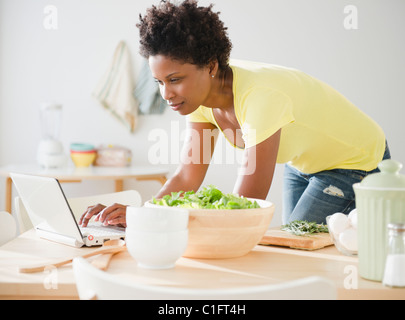 Black woman using laptop on dining room table Stock Photo