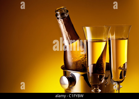 Champagne bottle in cooler and two champagne glasses. Isolated on a yellow. Stock Photo