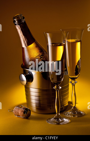 Champagne bottle in cooler and two champagne glasses. Isolated on a yellow. Stock Photo