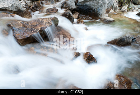 Fast creek runs through the rocky landscape and creates waterfalls. Stock Photo