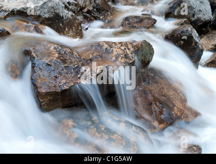 Fast creek runs through the rocky landscape and creates waterfalls. Stock Photo