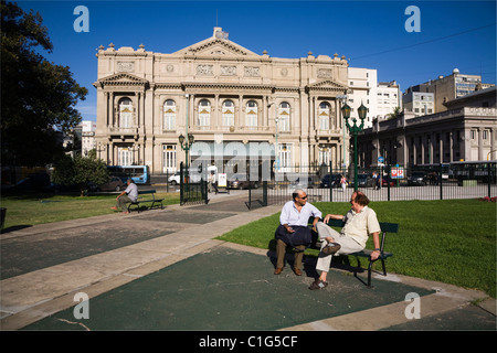 Two men sitting on a bench in front of Teatro Colon Stock Photo