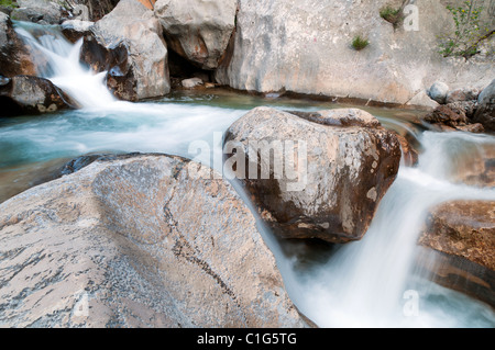 Fast creek runs through the rocky landscape and creates waterfalls. Stock Photo