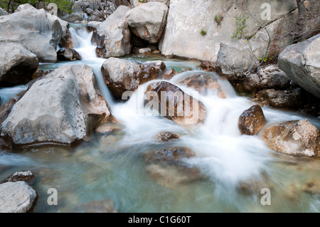 Fast creek runs through the rocky landscape and creates waterfalls. Stock Photo