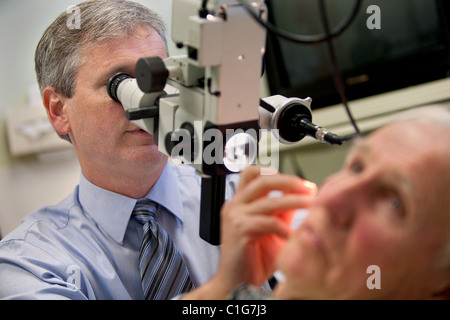 A doctor inserts a hearing aid into a patient. Stock Photo