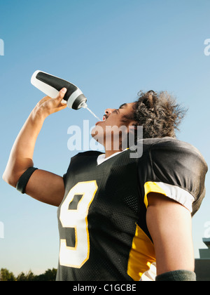 American football player drinking water from a bottle while standing on ...