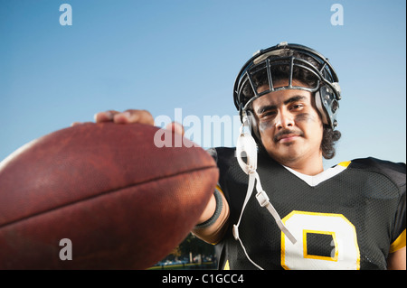 Hispanic football player holding football Stock Photo