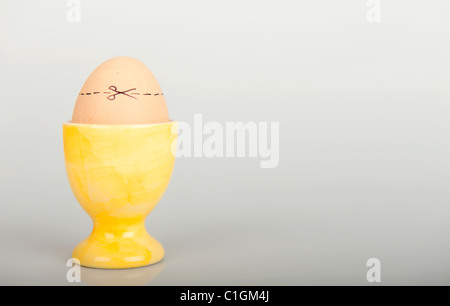 Stock photo of an egg in an egg cup with cut here lines across the shell. Stock Photo