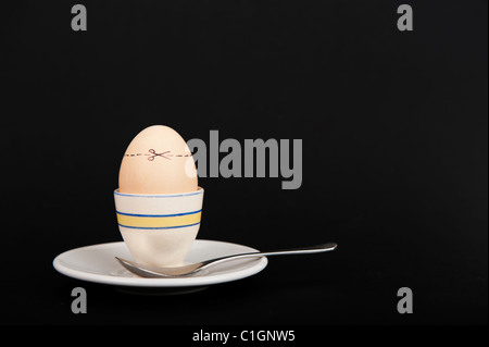 Stock photo of an egg in an egg cup with cut here lines across the shell. Stock Photo