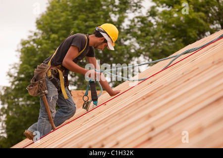 Carpenter using safety strap on the roof of a house under construction Stock Photo