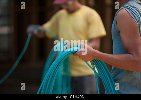 Carpenters coiling air hoses Stock Photo