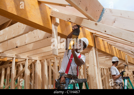 Carpenter using a sawzall on the roof boards of a house under construction Stock Photo