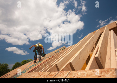 Carpenter holding a nail gun on the roof of a house under construction Stock Photo