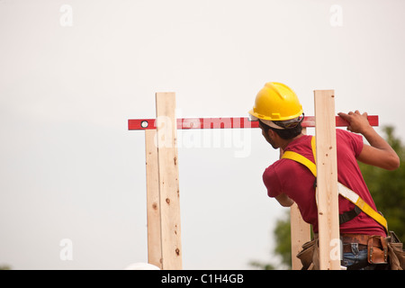 Hispanic carpenter measuring chimney posts with a level at a house under construction Stock Photo