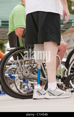Man with prosthetic leg standing with a man in wheelchair with spinal cord injury Stock Photo