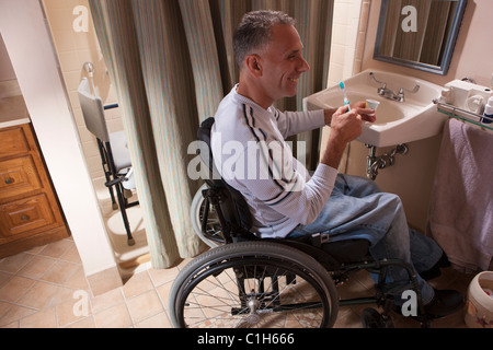 Man with spinal cord injury in a wheelchair brushing his teeth Stock Photo