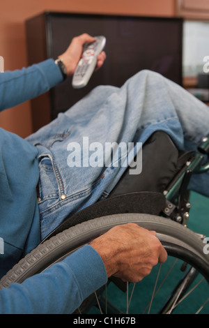 Man with spinal cord injury in a wheelchair using a remote control Stock Photo