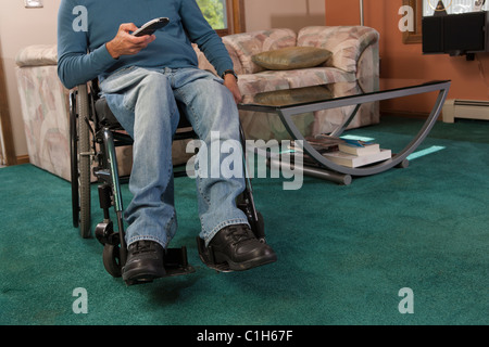 Man with spinal cord injury in a wheelchair using a remote control Stock Photo