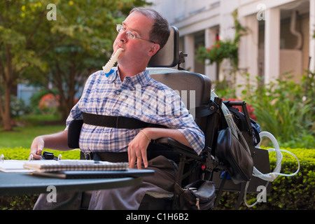 Businessman with Duchenne muscular dystrophy using breathing ventilator and doing paperwork at a cafe Stock Photo