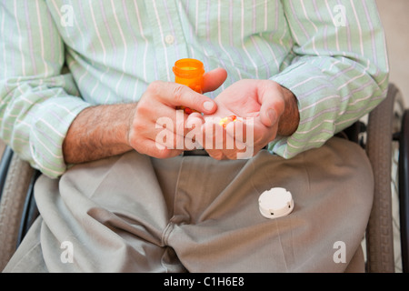 Man with spinal cord injury in a wheelchair taking medicine Stock Photo