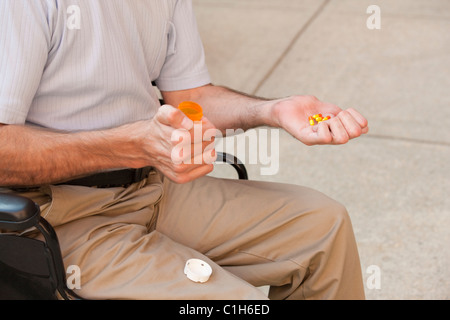 Man with Friedreich's Ataxia holding pills with degenerated hands Stock Photo