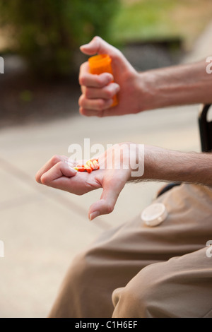 Man with Friedreich's Ataxia holding pills with degenerated hands Stock Photo