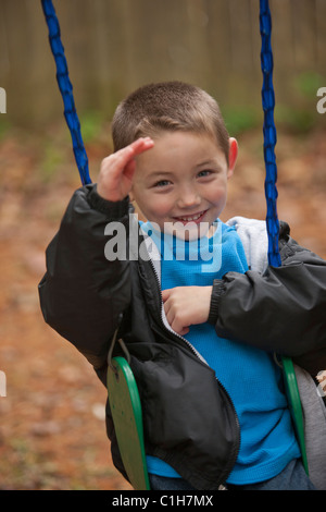 Boy signing the word 'Hello' in American Sign Language on a swing Stock Photo