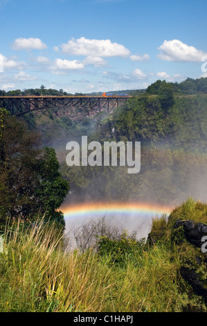 View of border bridge over the Batoka Gorge Zambezi River between Zambia and Zimbabwe shows rainbow in spray from Victoria Falls Stock Photo