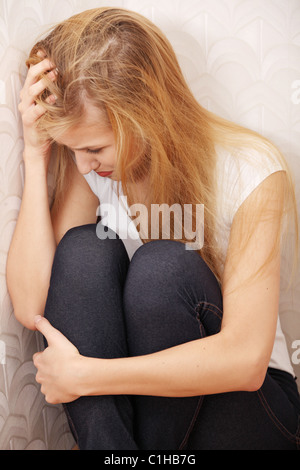 Scared abused woman sitting in the corner of the room. Stock Photo