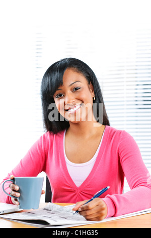 Happy young black female student looking in newspaper for job Stock Photo
