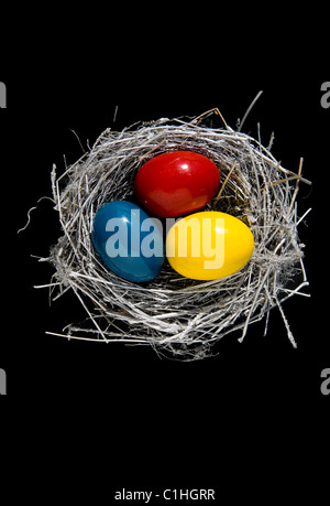 nest with three color Easter eggs on black background Stock Photo