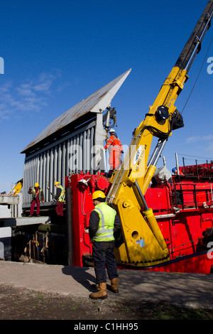 Telescopic crane unloading Alstom National Grid Electrical Transformer, Preston from the barge Terra Marique on the River Ribble, Lancashire, UK Stock Photo