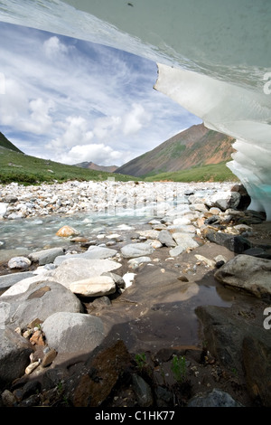 Wavy ice glacier edge over stones. Coast of mountain river Eheger. East Sayan mountains. Buryat republic. Russia. Stock Photo