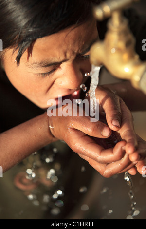 Nepali girl drinking water in Nepal Stock Photo