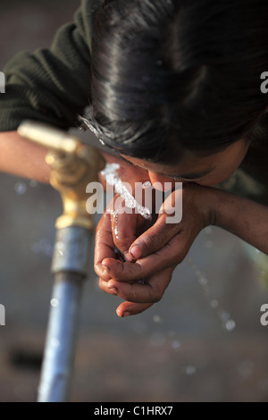 Nepali girl drinking water in Nepal Stock Photo