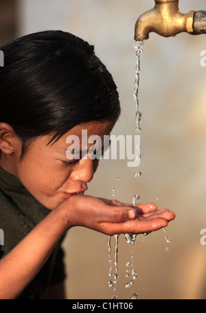 Nepali girl drinking water in Nepal Stock Photo