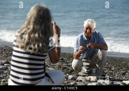 Senior woman taking picture of man on beach, Italy Stock Photo