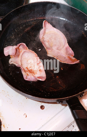 Bacon frying in pan Stock Photo