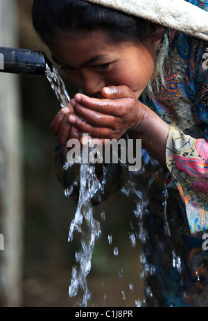 Nepali girl drinking water in Nepal Stock Photo