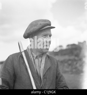 1950s, historical photograph of a shepherd wearing a cloth cap and with crook on his shoulder, a common site in the English countryside in this era. Stock Photo