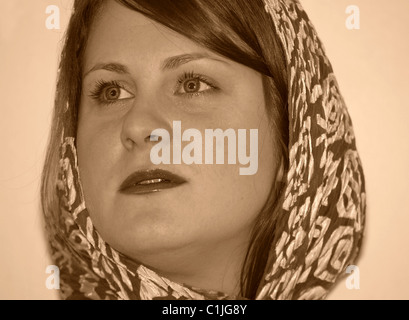 This is a stock portrait of a pretty Caucasian woman in her twenties, wearing a scarf in a sepia colored image. Light background Stock Photo