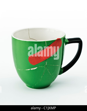 Broken green Mug glued together with red plaster Stock Photo