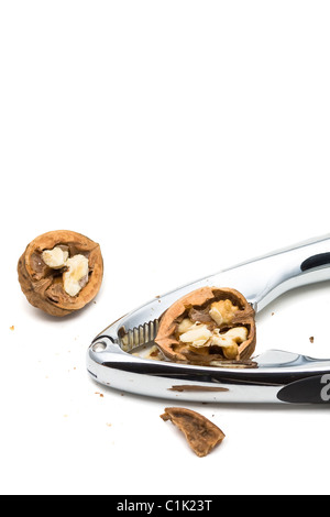 Cracking walnuts with nutcracker over white background Stock Photo